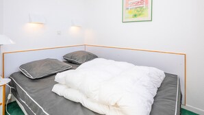 A neatly made bed with a white comforter and two gray pillows, a bedside table with a lamp, and a framed picture on the wall. - Family apartment 6 pers. with balcony in Avoriaz (Avoriaz)