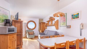 A cozy kitchen with wooden cabinets, a round mirror, a dining table with chairs, and a coffee maker. - Family apartment 6 pers. with balcony in Avoriaz (Avoriaz)