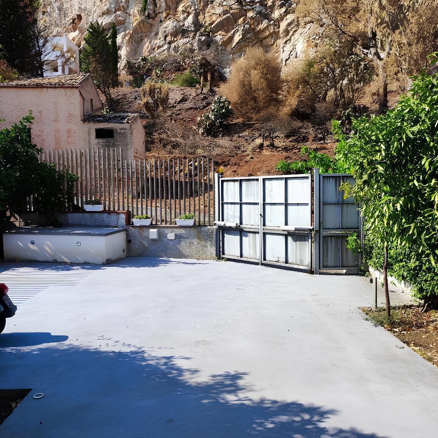 Ein verschlossenes Tor mit einem Betonweg, der zu einem Gebäude führt.