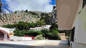 Un espace extérieur moderne, aménagé en patio, avec une piscine, un chemin en briques et une vue sur une colline parsemée de bâtiments.