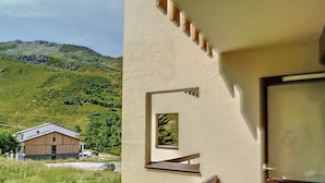 Un bâtiment doté d’un balcon donnant sur un paysage verdoyant et une montagne.