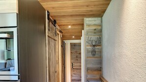 Un couloir intérieur au décor en bois, avec un plafond rustique et une tête de cerf décorative accrochée au mur.