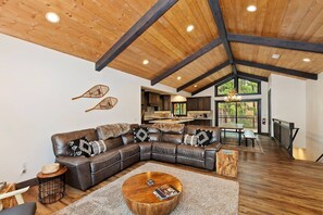 Amplia sala de estar con un sofá seccional grande, una mesa de centro de madera y vistas al exterior.
