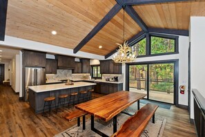 A modern kitchen with a large island, dark cabinetry, and a wooden ceiling.