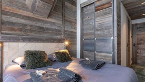 Une chambre avec un plafond en bois, un lit doté d’une tête de lit et un grand miroir.
