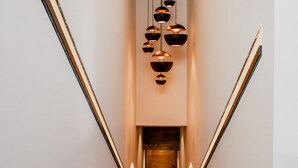 Un escalier moderne au design minimaliste, avec une porte en bois en bas et des luminaires aux formes géométriques en haut.