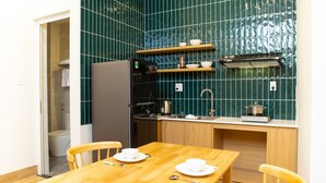 A compact kitchen with a wooden table and chairs, a sink, and a stove. - Vy's House Phanthiet Hotel (Phu Thuy)