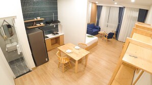 A compact living space with a kitchenette, a dining area, and a seating area with a sofa and chairs. - Vy's House Phanthiet Hotel (Phu Thuy)