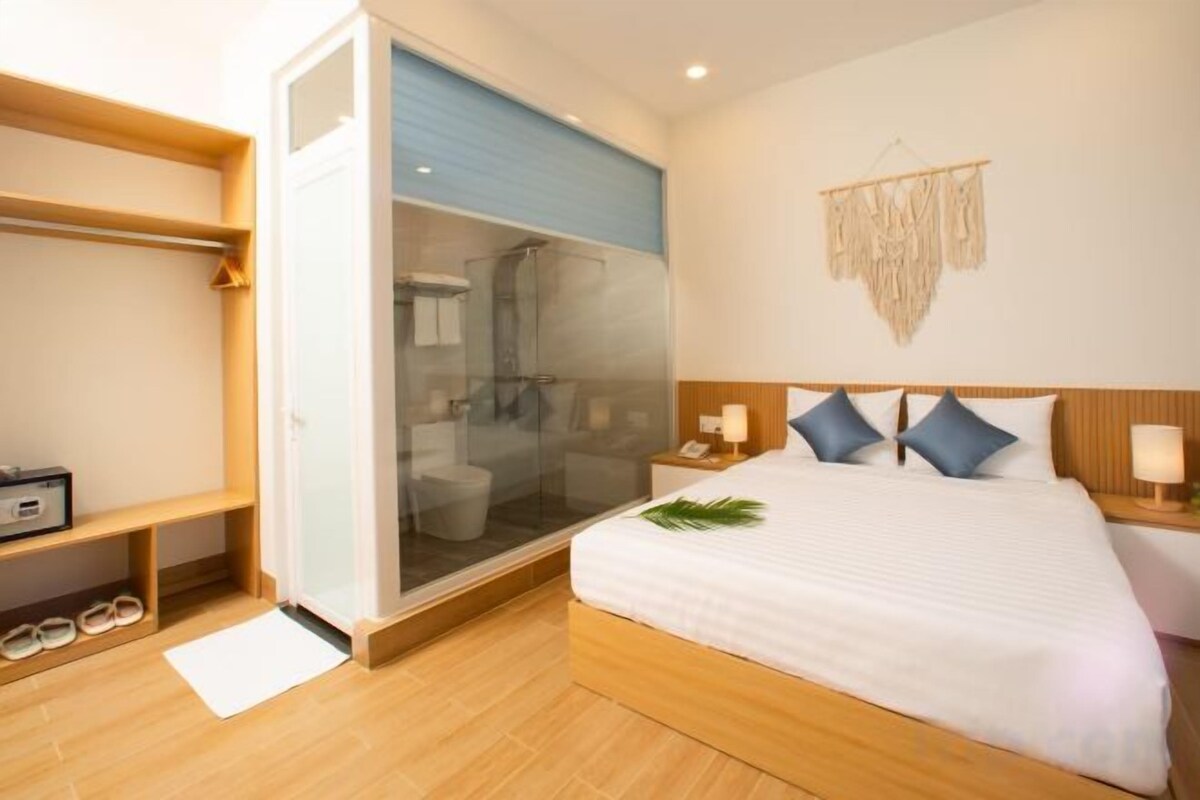 A hotel room with a bed, bedside tables, a wardrobe, and a shower area.