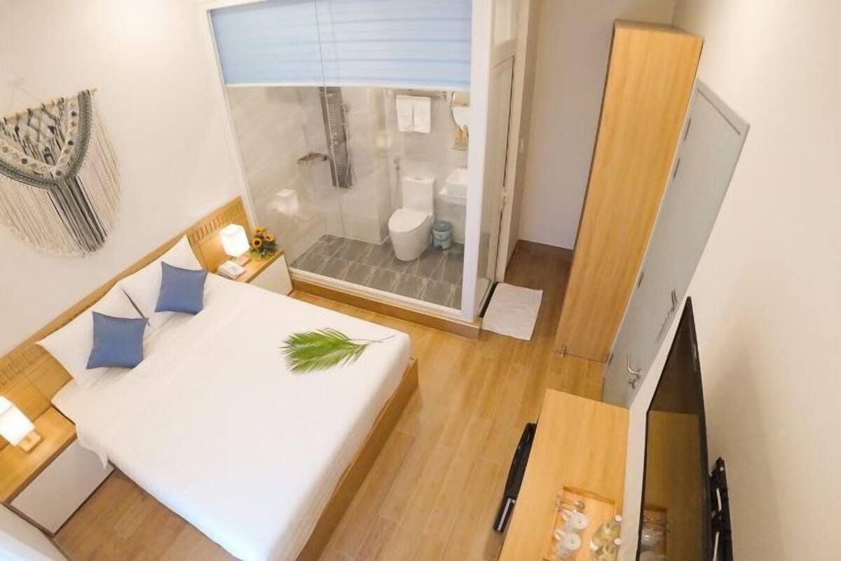 A hotel room with a bed, a desk, a shower, and a wardrobe.
