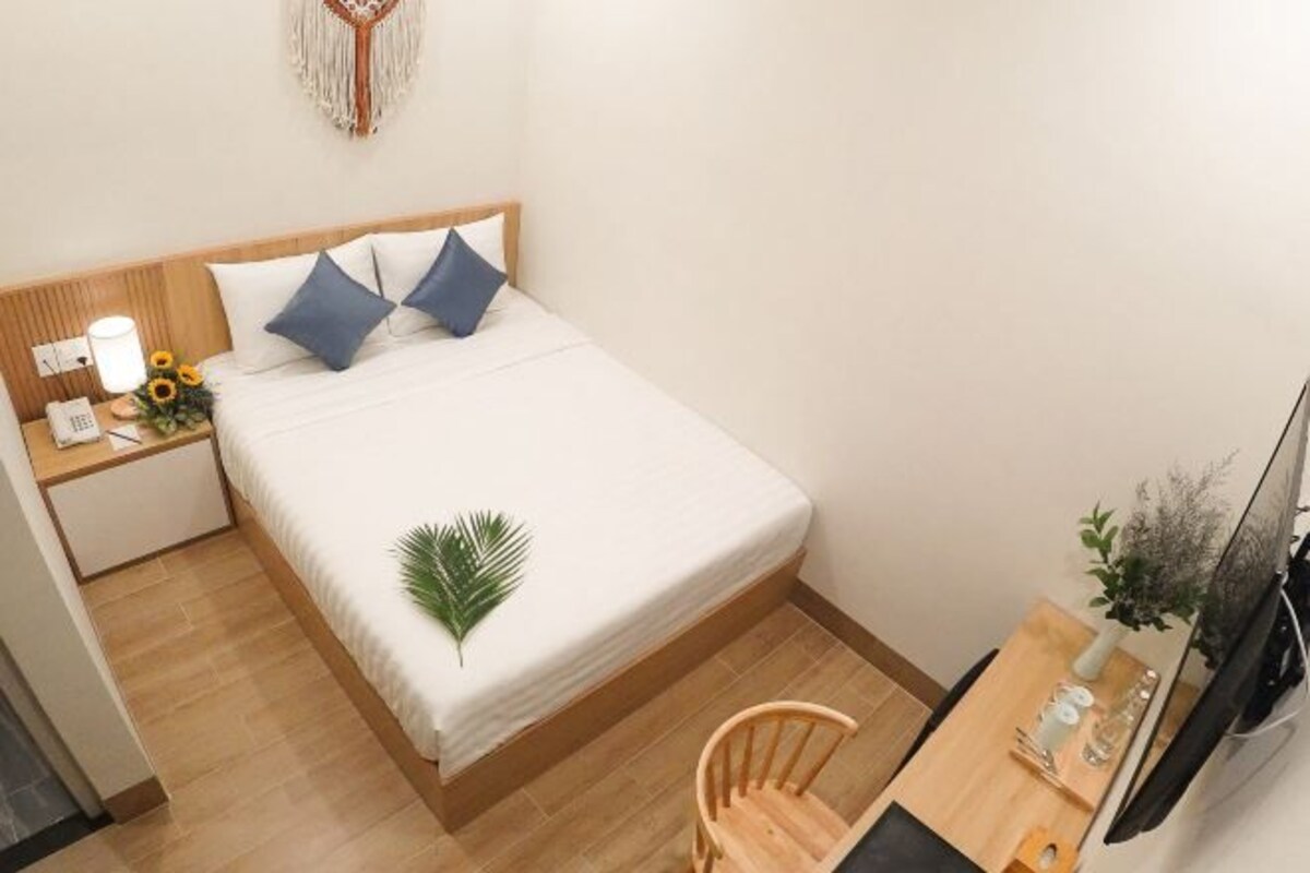 A small, neatly arranged room with a bed, a desk, and a chair.
