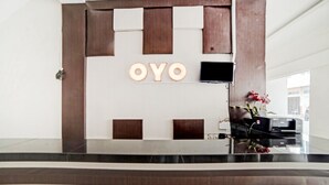 A reception desk with a wooden panel design and the name "OYO" illuminated above it. - Hotel O Stm Suite Near Amplas Bus Terminal (Medan)