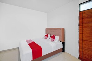 A neatly made bed with a white and red bedspread, a wooden headboard, and two red pillows. - Hotel O Stm Suite Near Amplas Bus Terminal (Medan)
