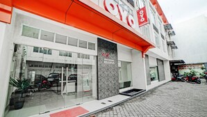 A modern building with a glass facade, a red awning, and a sign for 'OYO'. - Hotel O Stm Suite Near Amplas Bus Terminal (Medan)