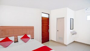 A hotel room with a bed, a wooden door, a white wall, and a sink. - Hotel O Stm Suite Near Amplas Bus Terminal (Medan)