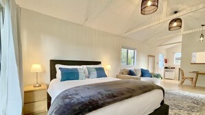 A spacious bedroom with a large bed, bedside tables, a desk, and a chair.