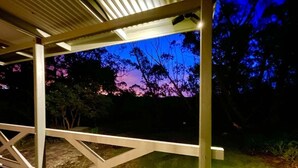 A covered outdoor area with a view of trees and a sunset.