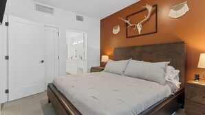 A bedroom with a large bed, a nightstand, a dresser, and a wall-mounted mirror. - Tumbleweed -  Walk to Coffee + Dining + Garage (Shawnee)