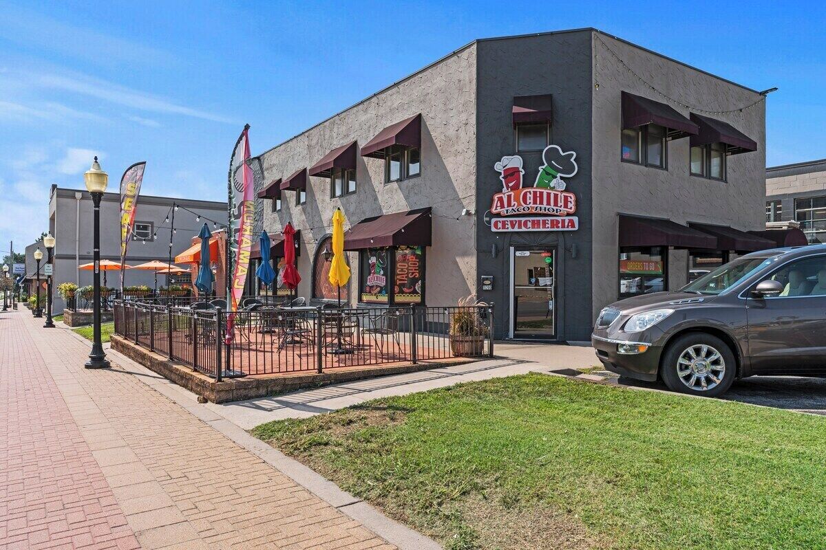 Un bâtiment avec une enseigne indiquant le restaurant « Al Cheif Exotico », des tables à l’extérieur et une voiture garée.