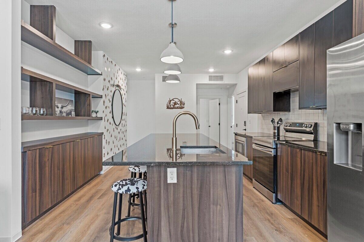 Una cocina moderna con una isla central, electrodomésticos de acero inoxidable y armarios de madera.