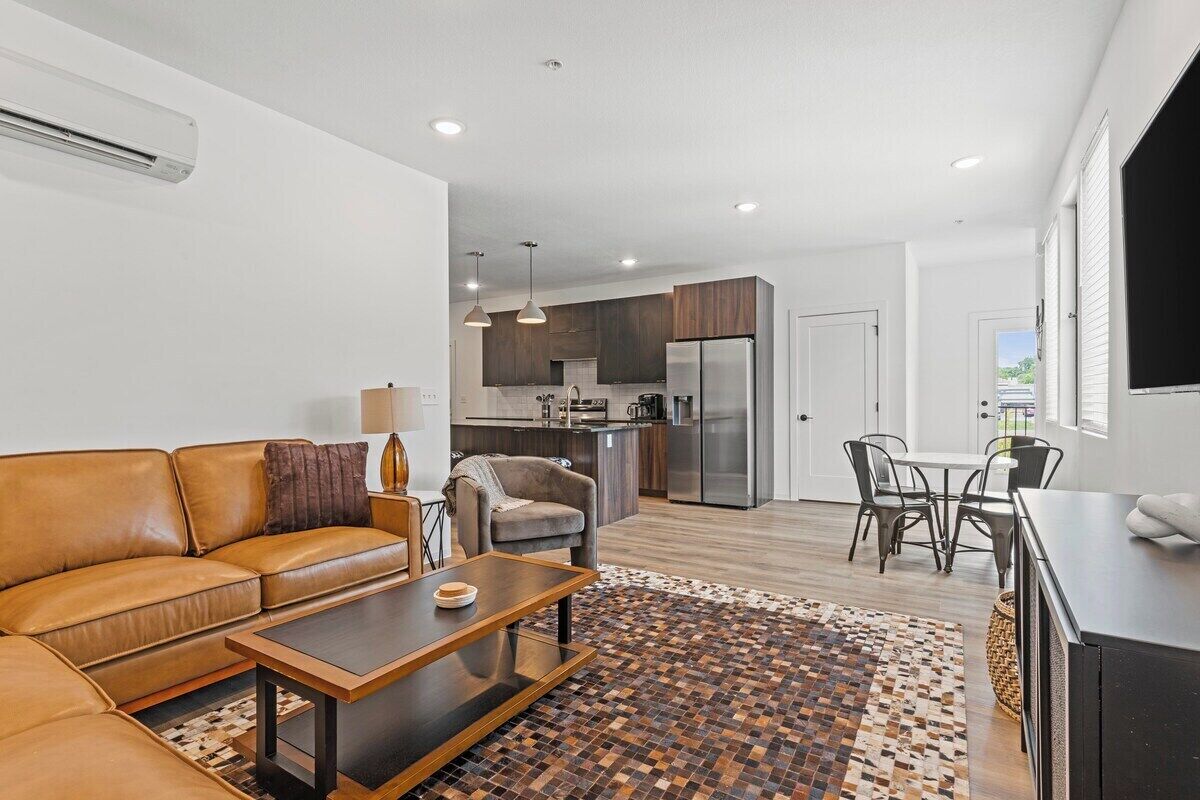A modern living room with a leather sofa, a coffee table, and a patterned rug.