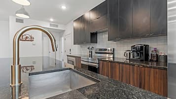 A modern kitchen with stainless steel appliances, a granite countertop, and dark wooden cabinets.