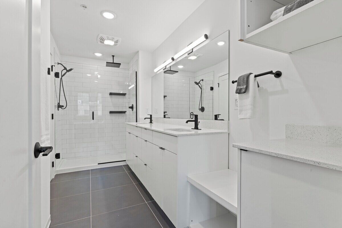 A modern bathroom with a walk-in shower, a vanity with a mirror, and a towel rack.