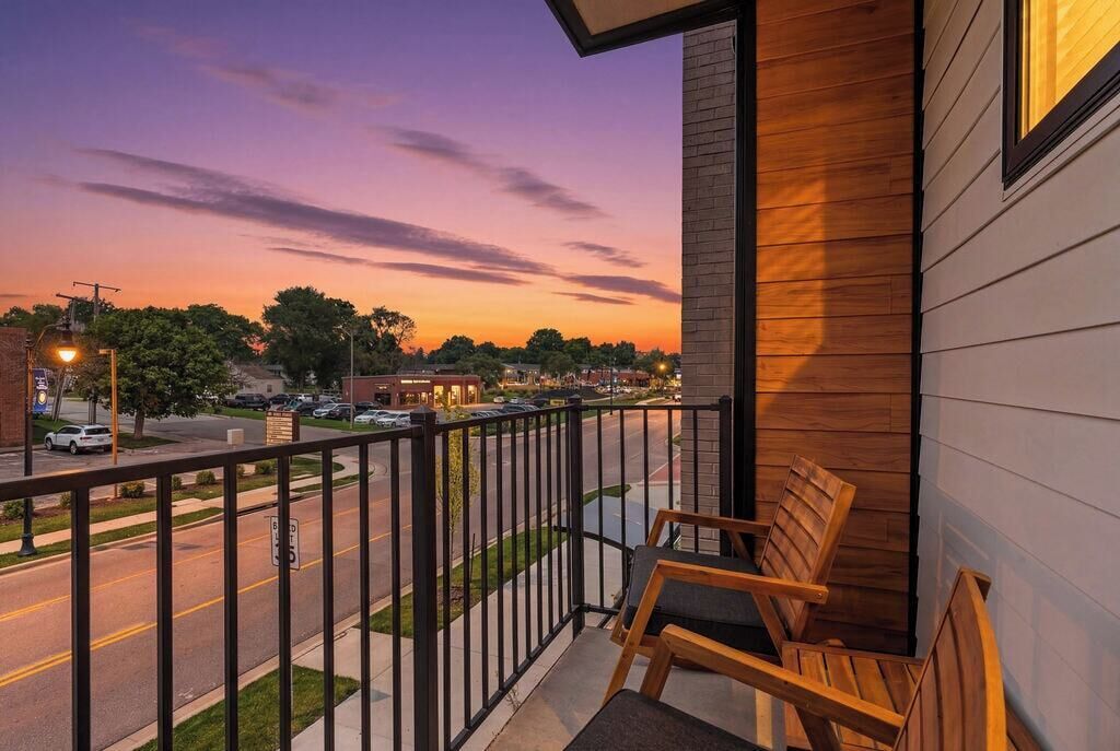 Varanda com vista para uma rua e árvores ao entardecer.