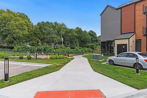 Ein Weg, der zu einem Gebäude mit Parkplatz und Grünflächen im Hintergrund führt.