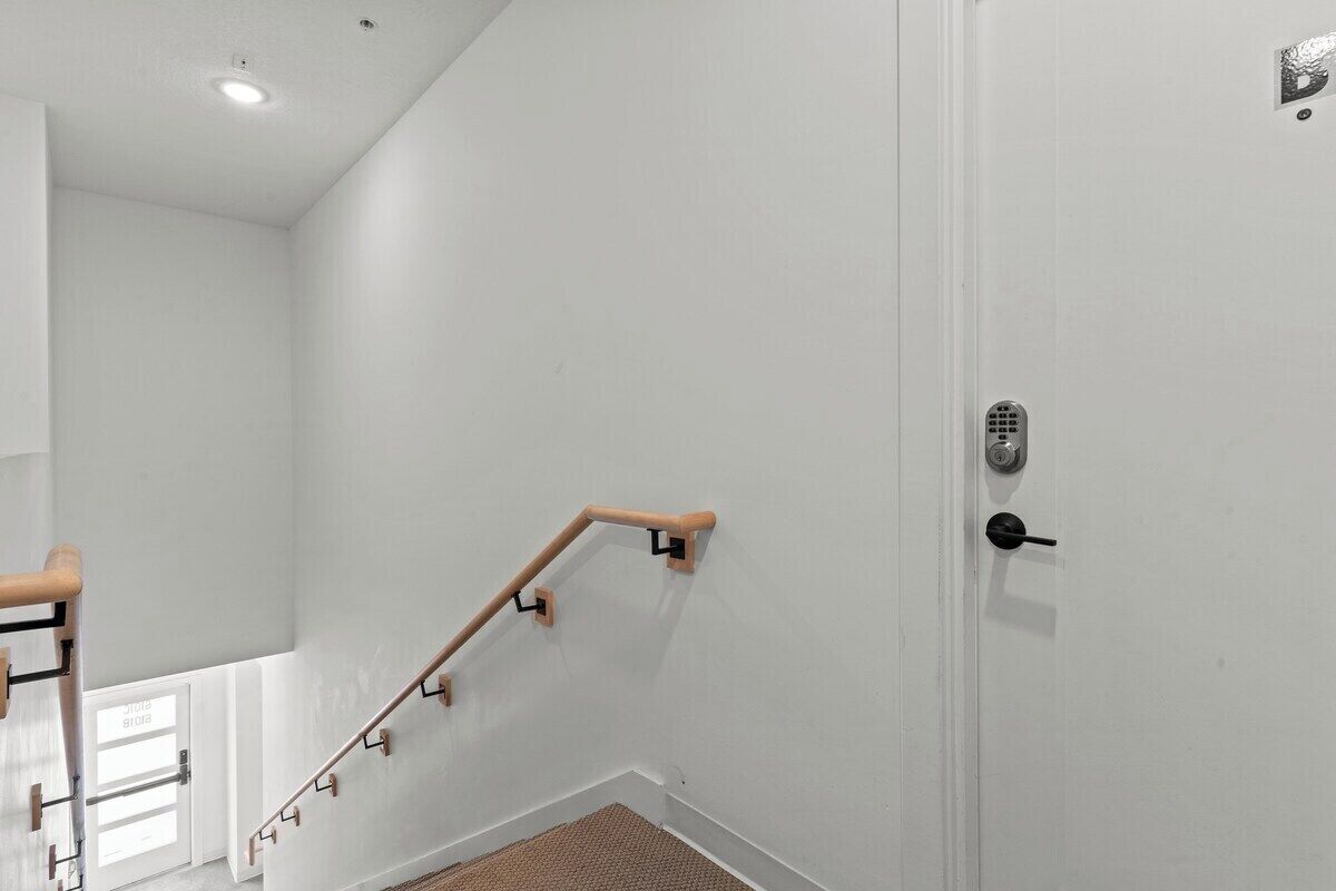 Un escalier avec une rampe, une porte avec une serrure et une fenêtre avec des stores.
