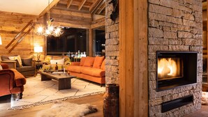 A cozy living room with a stone fireplace, wooden beams, and a rustic decor. - Luxury chalet for 12 near slopes, with sauna (Saint-Martin-de-Belleville)