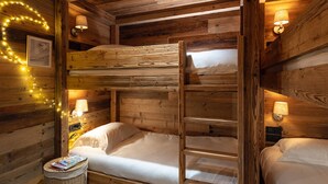 A cabin-style room with a bunk bed, two bedside lamps, and string lights. - Luxury chalet for 12 near slopes, with sauna (Saint-Martin-de-Belleville)