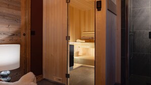 A modern bathroom with a wooden interior, a glass shower enclosure, and a visible sauna area. - Luxury chalet for 12 near slopes, with sauna (Saint-Martin-de-Belleville)
