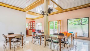 Una habitació àmplia amb un gran taulell i cadires, un sostre de fusta i vista a zones verdes a l'exterior.