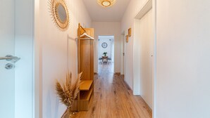 A hallway with a wooden bench, a wall-mounted mirror, and a hanging coat rack. - Tolle Ferienwohnung in Ruhiger Lage! (Eilsum)