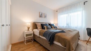 A bedroom with a bed, bedside table, lamp, and a chair. - Tolle Ferienwohnung in Ruhiger Lage! (Eilsum)