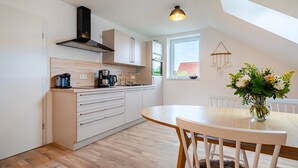 Una cucina moderna con piano cottura integrato, macchina per il caffè e zona pranzo con tavolo e sedie.