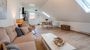 Spazioso loft con soffitto alto, zona pranzo, soggiorno con divano e tavolino, e lucernario.