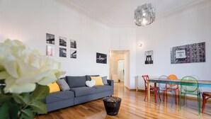 A modern living room with a grey sofa, a glass dining table, colorful chairs, and a wooden floor. - notaMi - Cinque Vie Top Floor City Center (Milan)