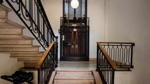 A staircase with a handrail, a metal gate, and a light fixture above. - notaMi - Cinque Vie Top Floor City Center (Milan)