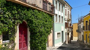 Une rue étroite bordée d’immeubles dotés de balcons et d’une porte rouge.
