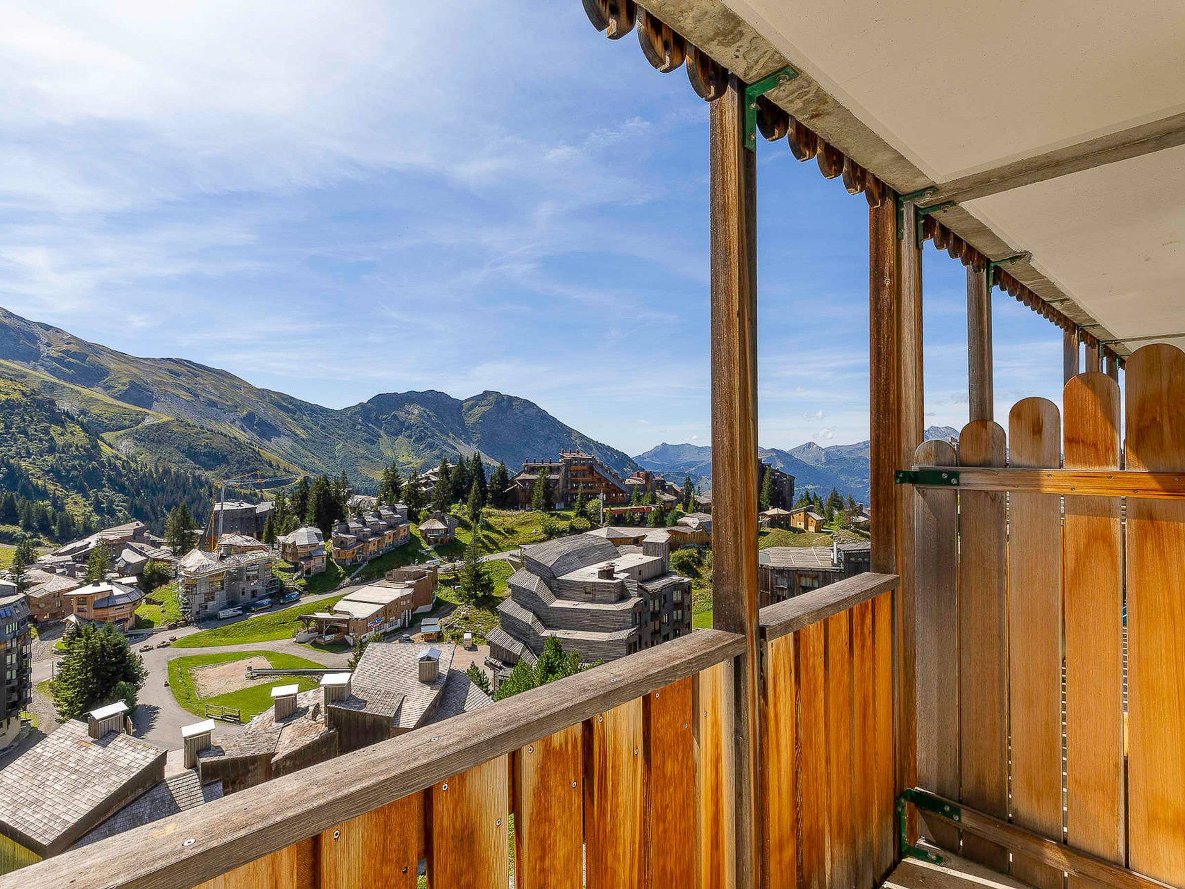 A balcony overlooking a mountainous village with traditional buildings and a clear sky.