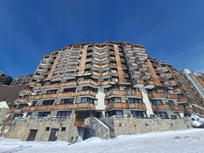 Un hôtel à plusieurs étages, doté de balcons, d’une façade en pierre et surplombant un ciel d’un bleu limpide.