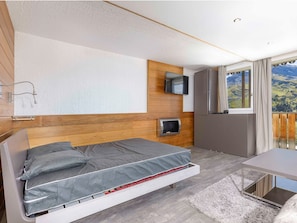 Une chambre moderne équipée d’un lit, d’une télévision, d’un radiateur intégré et d’une fenêtre donnant sur l’extérieur.