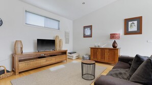 Ein modernes Wohnzimmer mit Flachbildfernseher, einer Holzunterhaltungsecke und einem gemütlichen Sofa.
