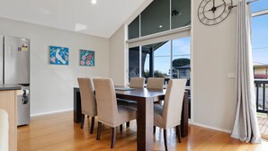 A dining area with a wooden table and chairs, a clock on the wall, and artwork on the wall. - Blue Bayou in Coronet Bay (Coronet Bay)