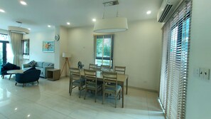 A modern living room with a dining area, featuring a sofa, chairs, a dining table, and a lamp. - Villa Royal Lotus Ha Long ( Standard villa, with shared swimming pool) (Hạ Long)