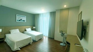 A hotel room with two beds, a television, a desk, and a window with curtains. - Villa Royal Lotus Ha Long (Hạ Long)