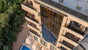 Un hotel moderno con varios balcones, piscina y zonas de estar al aire libre.