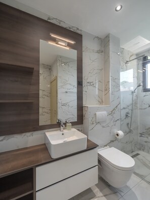 A modern bathroom with a marble vanity, a large mirror, a toilet, and a shower area. - Hotel Diman (Bar)